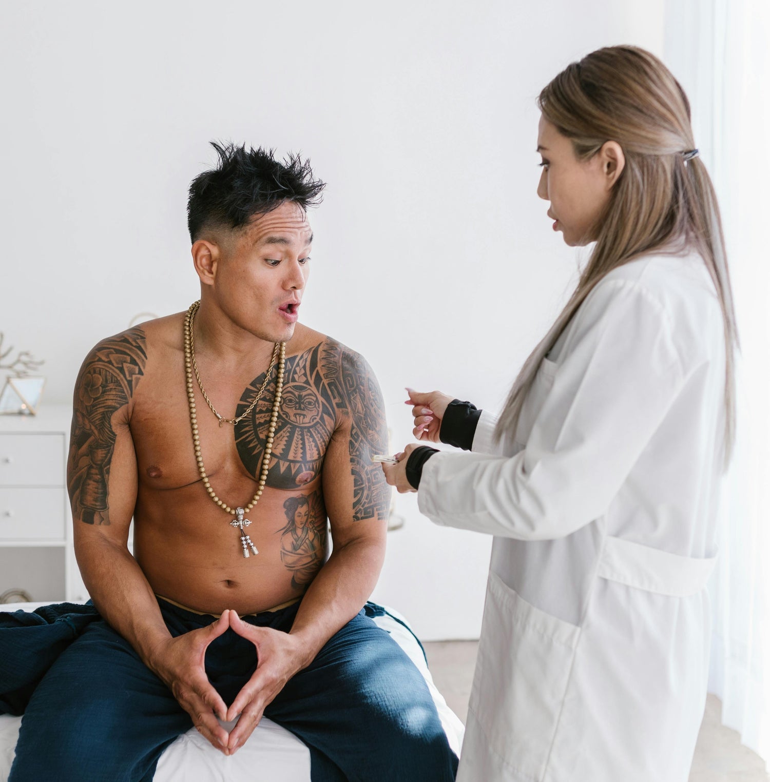Female doctor talking to tattooed patient in modern clinic.